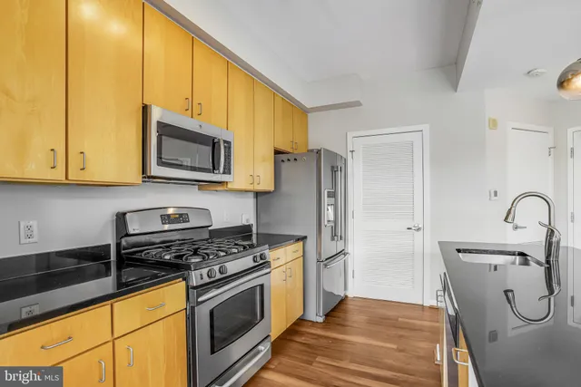a kitchen with stainless steel appliances granite countertop a refrigerator a stove a sink dishwasher a oven with a dining table and chairs with wooden floor