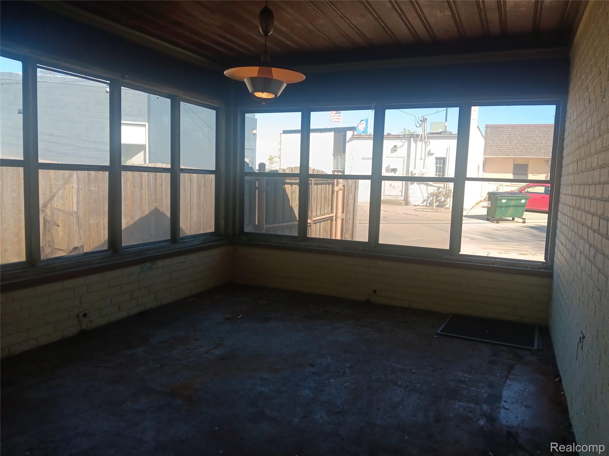 967 Washington Road Grosse Pointe, MI 48230 - Photo 6 of 15 Unfurnished sunroom featuring brick wall, concrete flooring, and wood ceiling