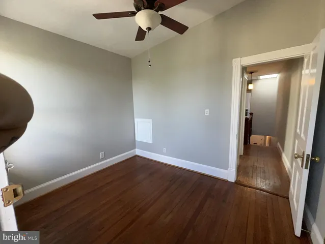 an empty room with wooden floor and fan