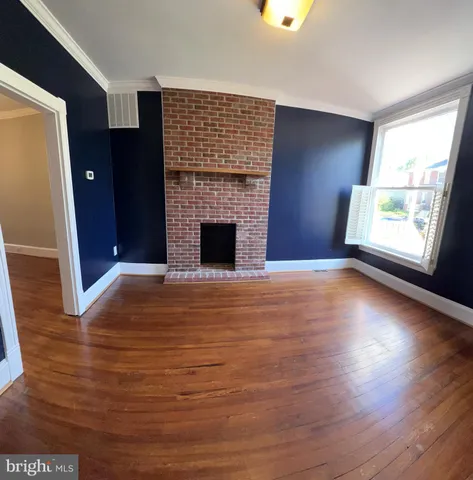 an empty room with wooden floor fireplace and windows