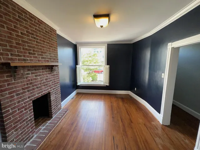 a view of empty room with wooden floor and fireplace