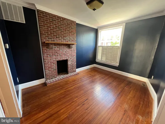 an empty room with wooden floor fireplace and windows