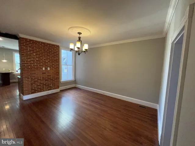 an empty room with wooden floor chandelier and windows