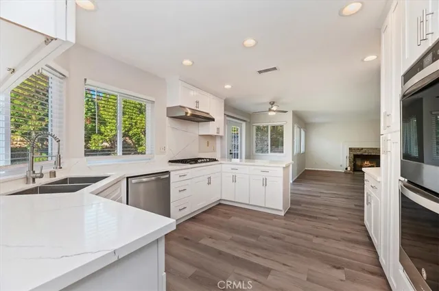 a large kitchen with granite countertop a large counter top a sink a window and stainless steel appliances