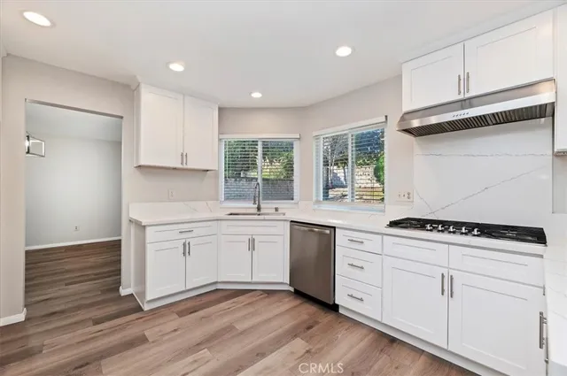a kitchen with stainless steel appliances granite countertop a stove a sink and white cabinets