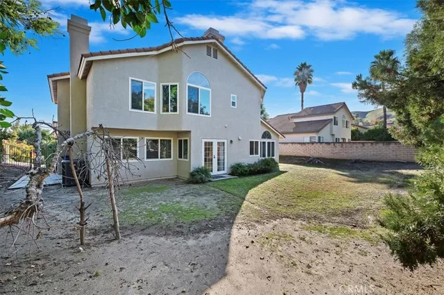 a view of a white house next to a yard with big trees