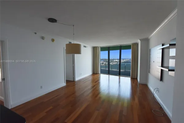 a view of an empty room with wooden floor and a window