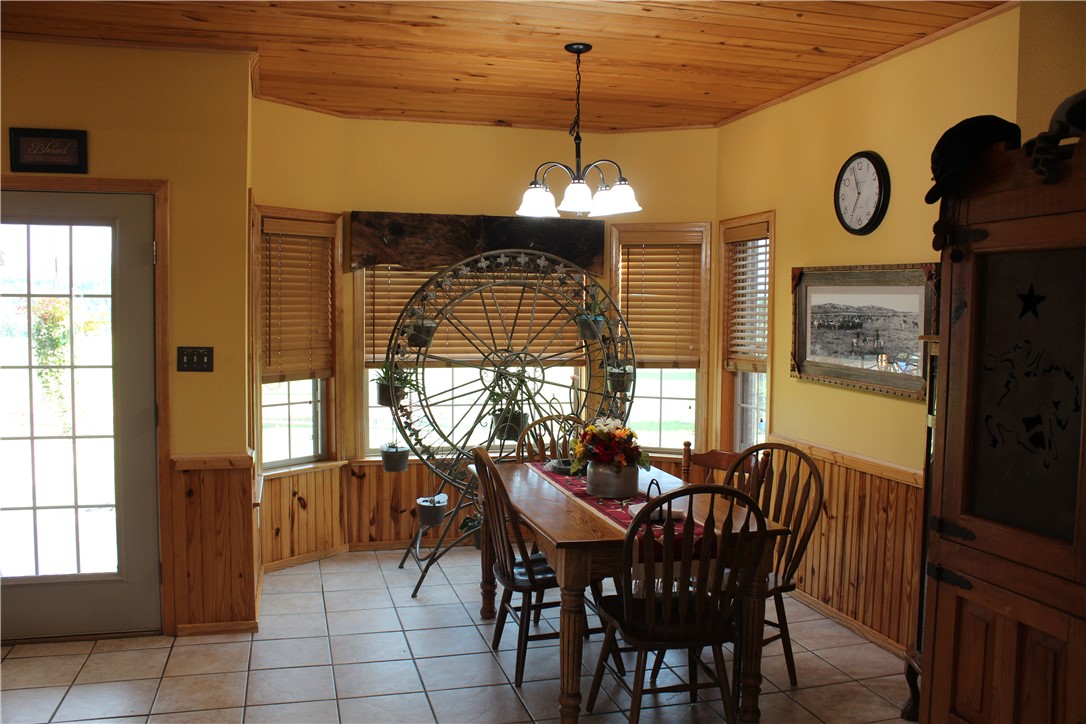 2210 Weiterer Road Scranton, AR 72863 - Photo 16 of 49 Bay window dining area featuring a wood-panel ceiling, wainscoting, and tile flooring