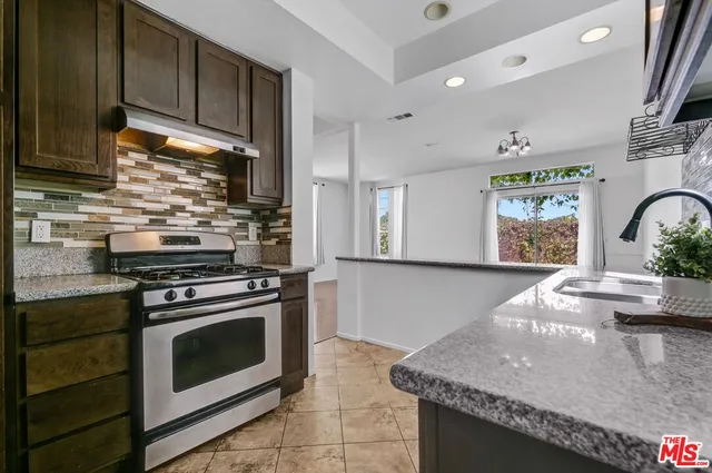 a kitchen with stainless steel appliances granite countertop a stove a sink and a microwave
