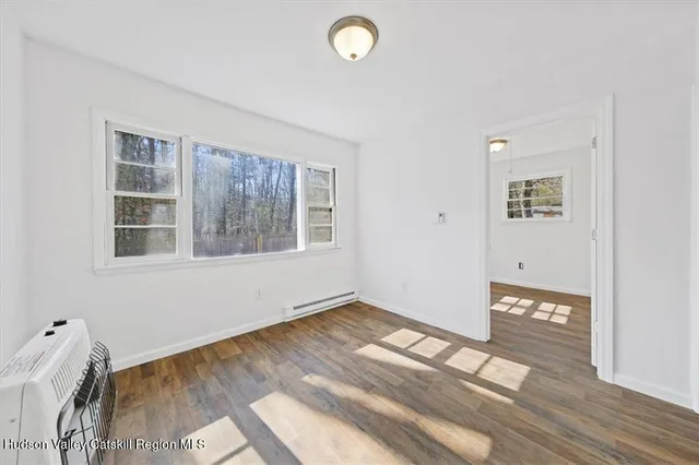 a view of an empty room with wooden floor and a window