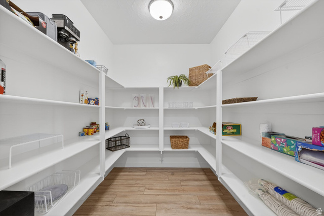 1165 West Union Bench Drive Mapleton, UT 84664 - Photo 20 of 61 Spacious walk-in pantry featuring extensive white shelving, corner shelving units, wood-finish flooring, and a flush-mount ceiling light fixture