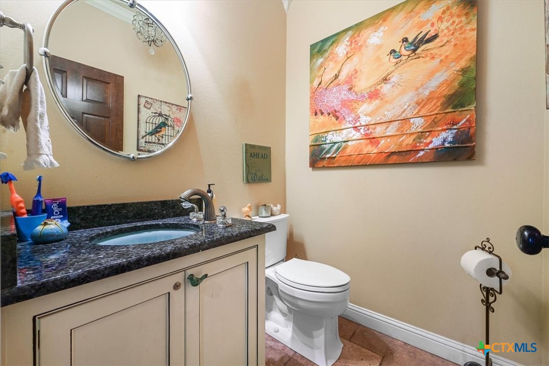 615 Benchmark Trail Belton, TX 76513 - Photo 30 of 36 a bathroom with a granite countertop toilet a sink and mirror