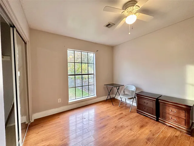 a view of an empty room with a window and wooden floor