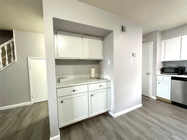 a kitchen with white cabinets and wooden floor