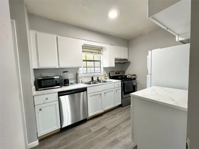 a kitchen with a sink a stove a refrigerator and cabinets