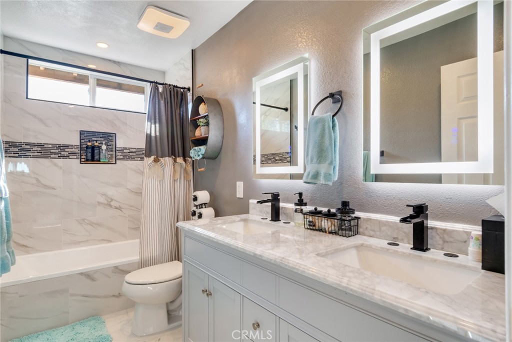 20885 Bakal Drive Riverside, CA 92508 - Photo 24 of 47 a bathroom with a granite countertop sink a toilet a mirror and bathtub