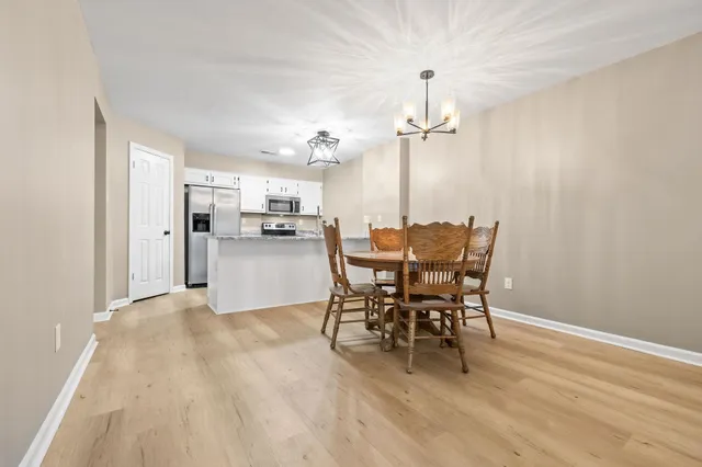 a view of a dining room and livingroom with furniture wooden floor a chandelier