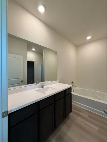 a bathroom with a sink vanity granite tub and a mirror
