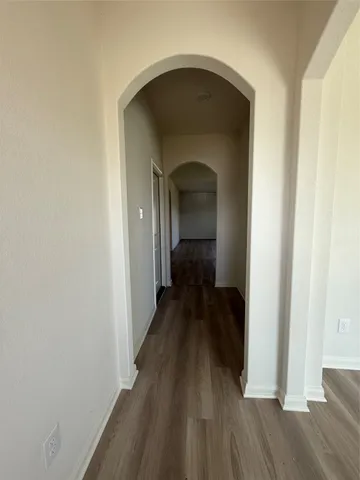 a view of a hallway with wooden floor and a bathroom