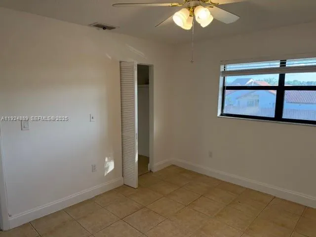an empty room with a chandelier fan and wooden floor