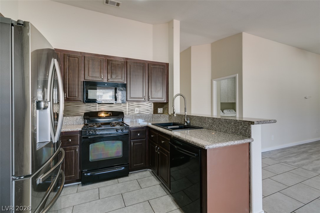 2028 Rustler Ridge Avenue North Las Vegas, NV 89031 - Photo 20 of 40 A well-appointed kitchen features dark wood cabinetry and contrasting light granite countertops.