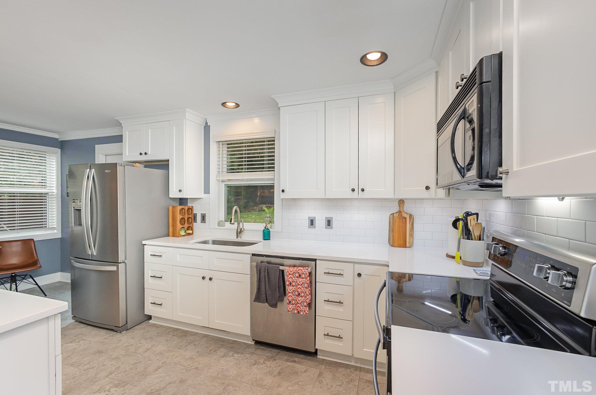 719 New Road Raleigh, NC 27608 - Photo 14 of 38 a kitchen with stainless steel appliances a stove a sink and a refrigerator