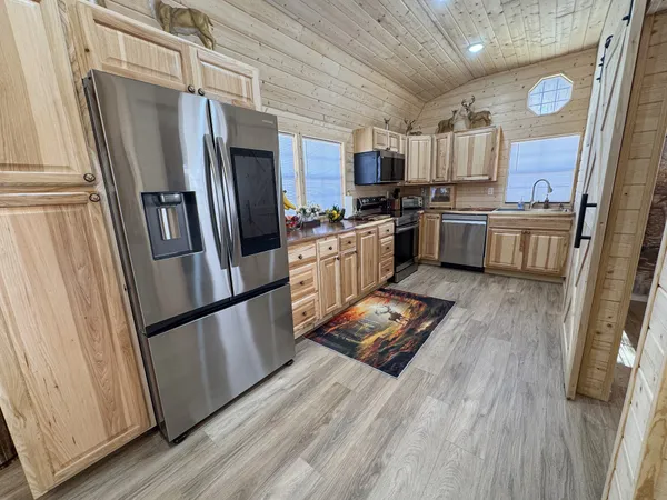 a kitchen with stainless steel appliances a refrigerator a sink a stove top oven and wooden floors
