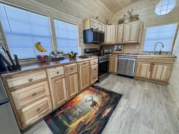 a kitchen with granite countertop a stove top oven a sink dishwasher and cabinets with wooden floor