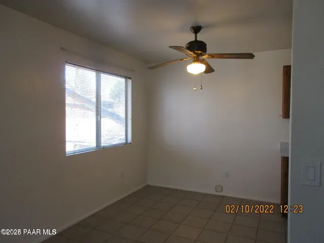 an empty room with ceiling fan and window