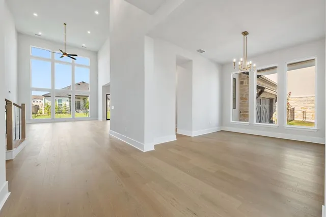 an empty room with wooden floor fan and windows