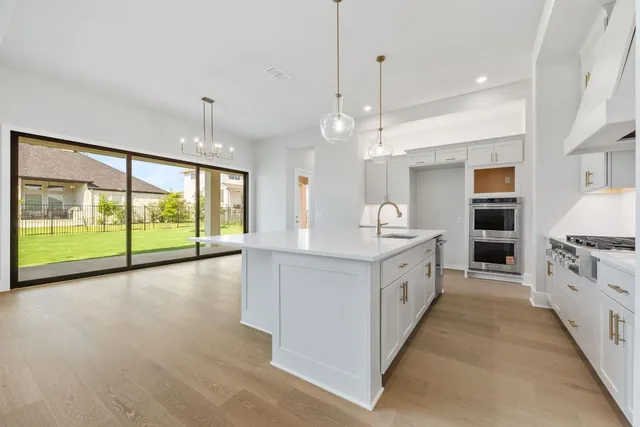 a large white kitchen with a large window a sink and stainless steel appliances