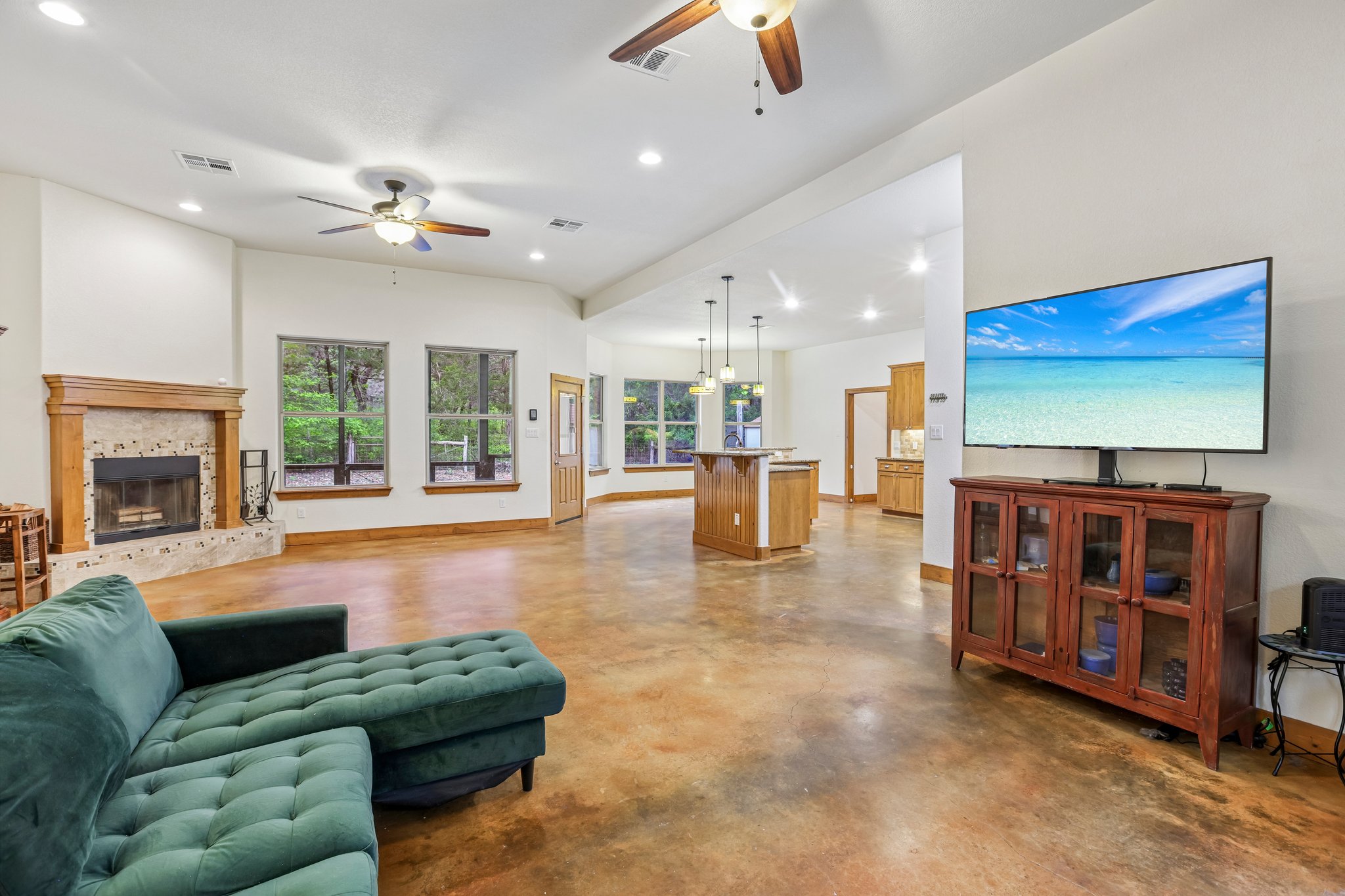 267 Corral Road Smithville, TX 78957 - Photo 13 of 40 Expansive living area featuring stained concrete flooring, a fireplace with a stone surround and wood mantel, multiple windows, and recessed lighting