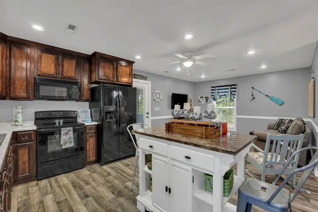 a kitchen with stainless steel appliances granite countertop a stove top oven a sink dishwasher a dining table and chairs with wooden floor