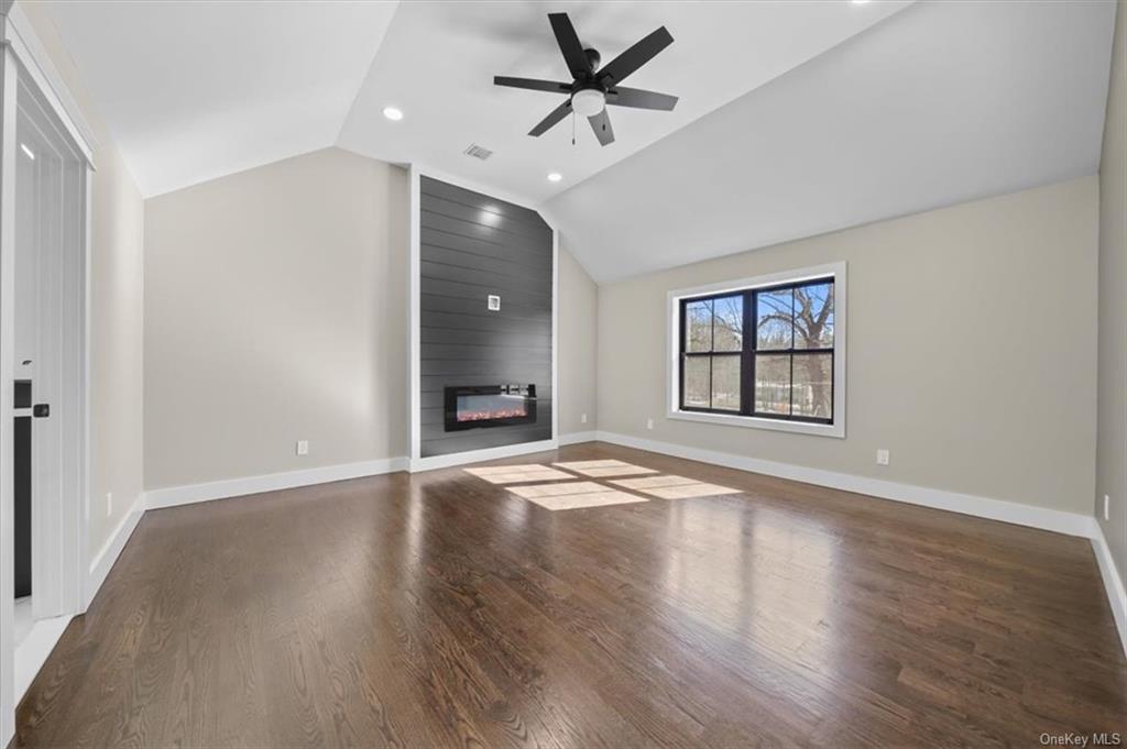 346 Shawanga Lodge Road Bloomingburg, NY 12721 - Photo 19 of 36 Unfurnished living room featuring a large fireplace, vaulted ceiling, ceiling fan, and dark hardwood / wood-style flooring