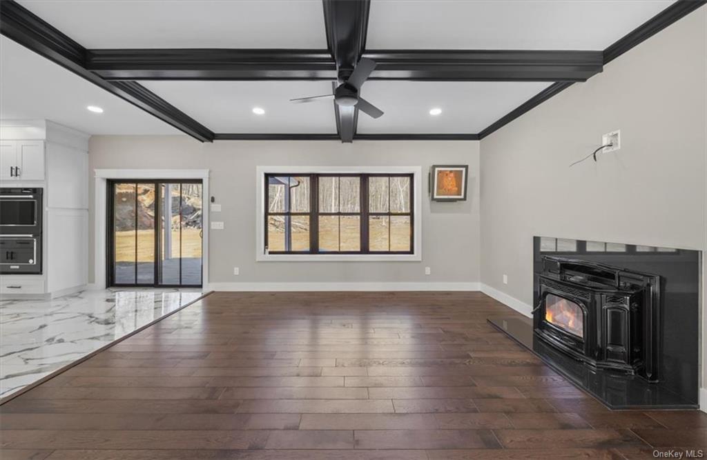 346 Shawanga Lodge Road Bloomingburg, NY 12721 - Photo 8 of 36 Unfurnished living room with dark hardwood / wood-style flooring, a wood stove, crown molding, beam ceiling, and ceiling fan