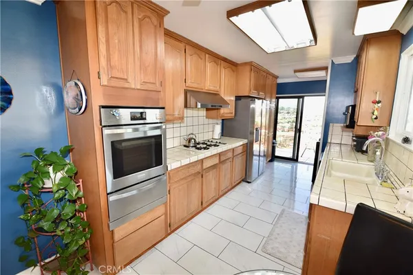 a kitchen with stainless steel appliances kitchen island granite countertop a refrigerator a stove a sink dishwasher and white cabinets with wooden floor