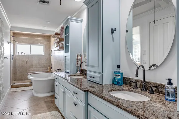 a bathroom with a granite countertop sink double mirror and a bathtub