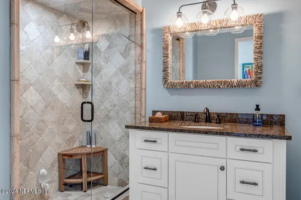 a bathroom with a granite countertop sink a mirror and shower