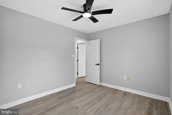 an empty room with wooden floor and ceiling fan