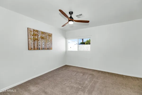 a view of an empty room with a ceiling fan and a window
