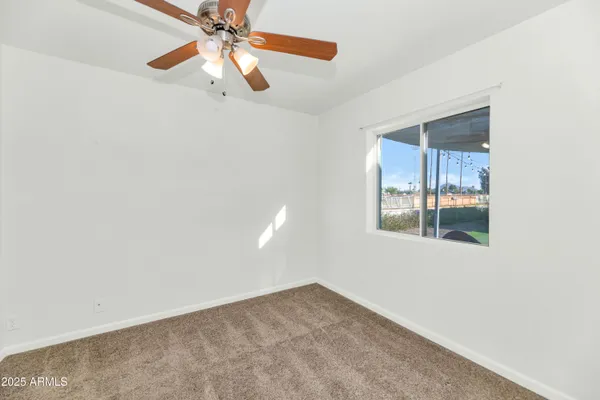 an empty room with windows and fan