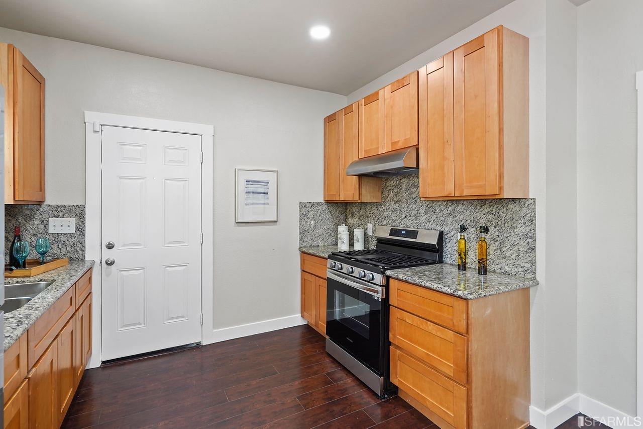 3036 14th Avenue Oakland, CA 94602 - Photo 24 of 35 a kitchen with stainless steel appliances granite countertop a stove a sink and a refrigerator with wooden floors
