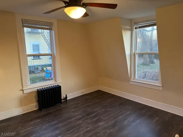 an empty room with wooden floor cabinet and windows
