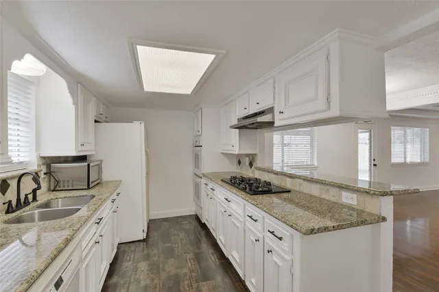 a kitchen with granite countertop a sink stove and cabinets
