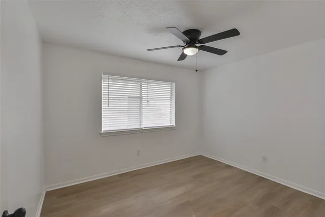 an empty room with a window and a fan