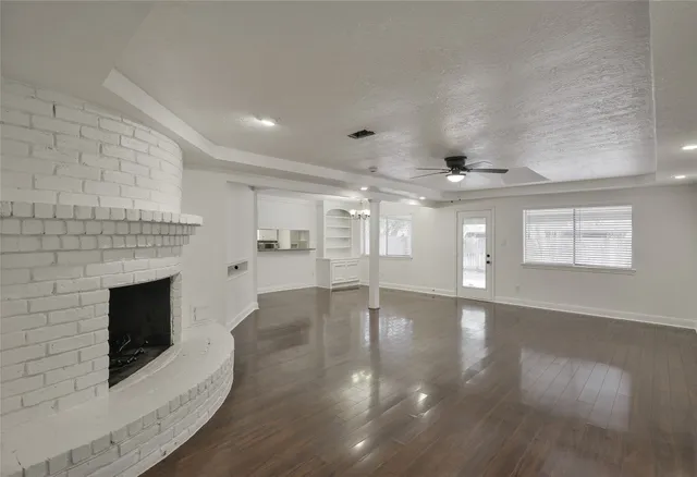 a view of an empty room with wooden floor fireplace and a window