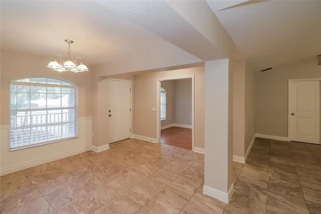an empty room with chandelier and windows