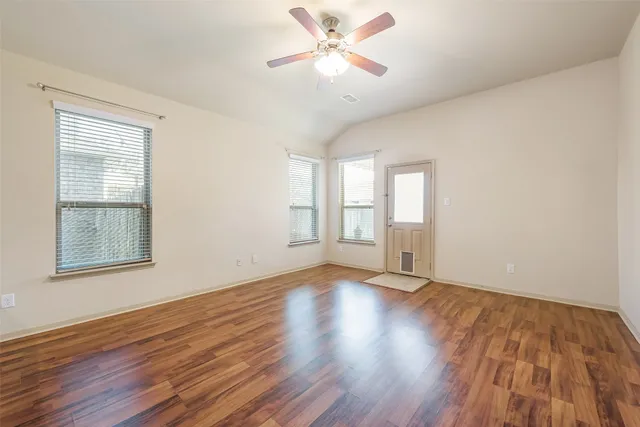 a view of an empty room with wooden floor and a window
