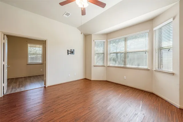 a view of an empty room with wooden floor and a window