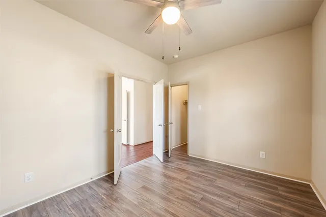 an empty room with wooden floor and a ceiling fan